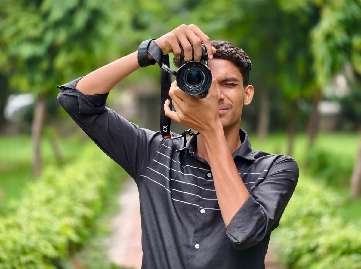 Een jonge mannelijke fotograaf maakt foto's in een weelderige groene buitenomgeving.