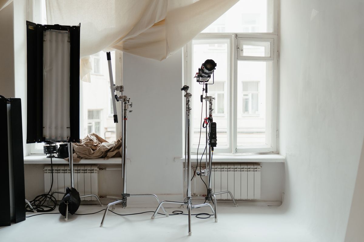 Een minimalistische fotostudio-opstelling met professionele verlichtingsapparatuur en natuurlijk licht van ramen.